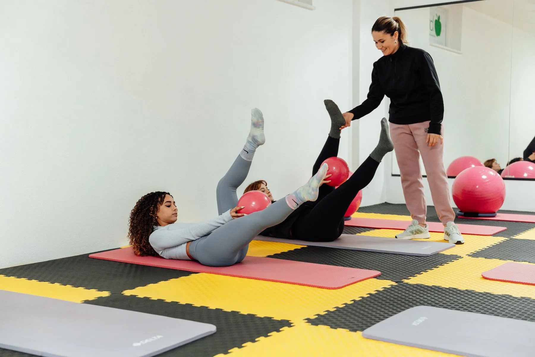 Instrutora orientando alunas em uma aula de pilates em grupo